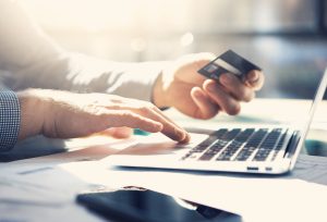 Closeup businessman working with generic design notebook. Online payments, hands keyboard. Blurred background, film effect