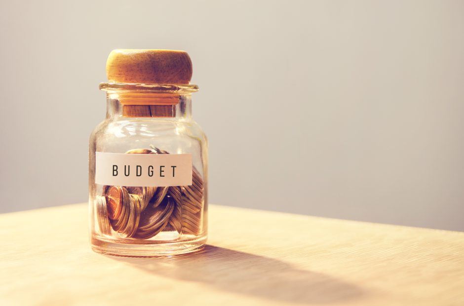 Glass bottle with coins in it with a label that says budget